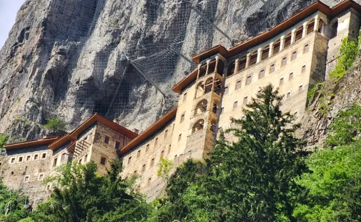 Sümela Manastırı’nın dış cephe duvarları ve keşiş hücrelerinin detaylı görünümü; dik kayalık yüzeye oyulmuş yapı ve üst bölümde görülen kaya güçlendirme ağları.